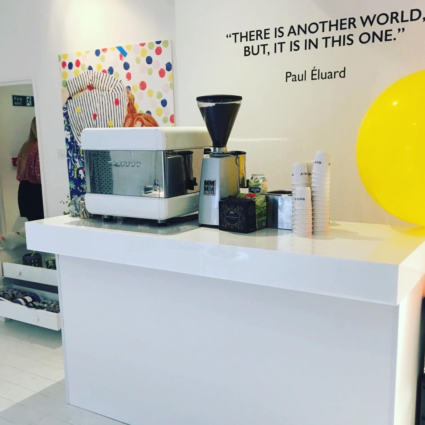 White mobile coffee bar with espresso machine and grinder at an indoor event